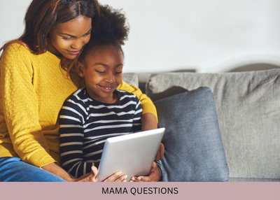 A woman and child smile while looking at a tablet together on a sofa.