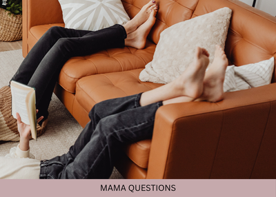 Two people relax with their feet up on a brown sofa, one holding an open book.